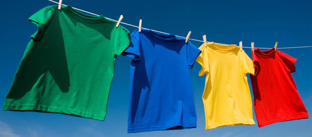 Green, blue, yellow and red t-shirts hanging on a washing line.