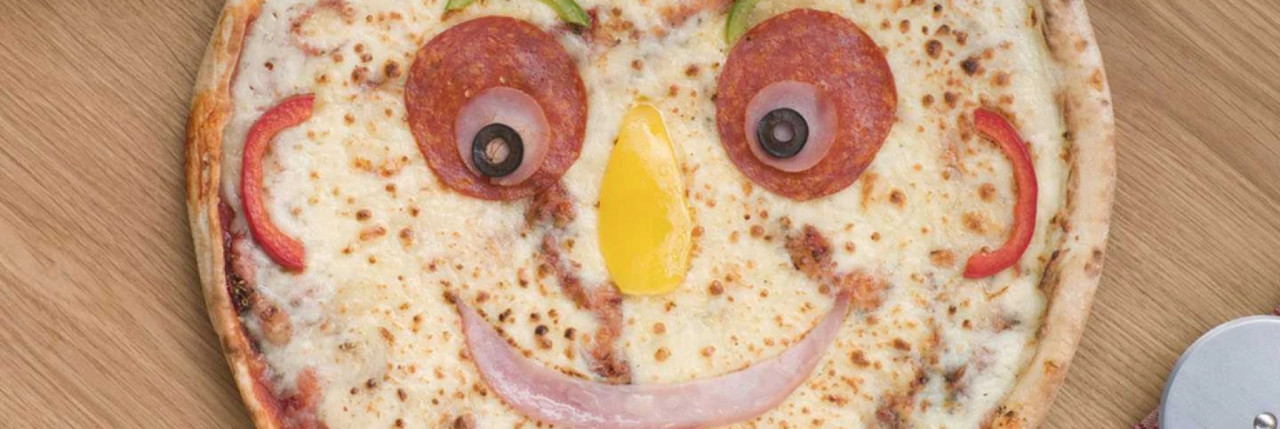 A pizza with a face made from ingredients