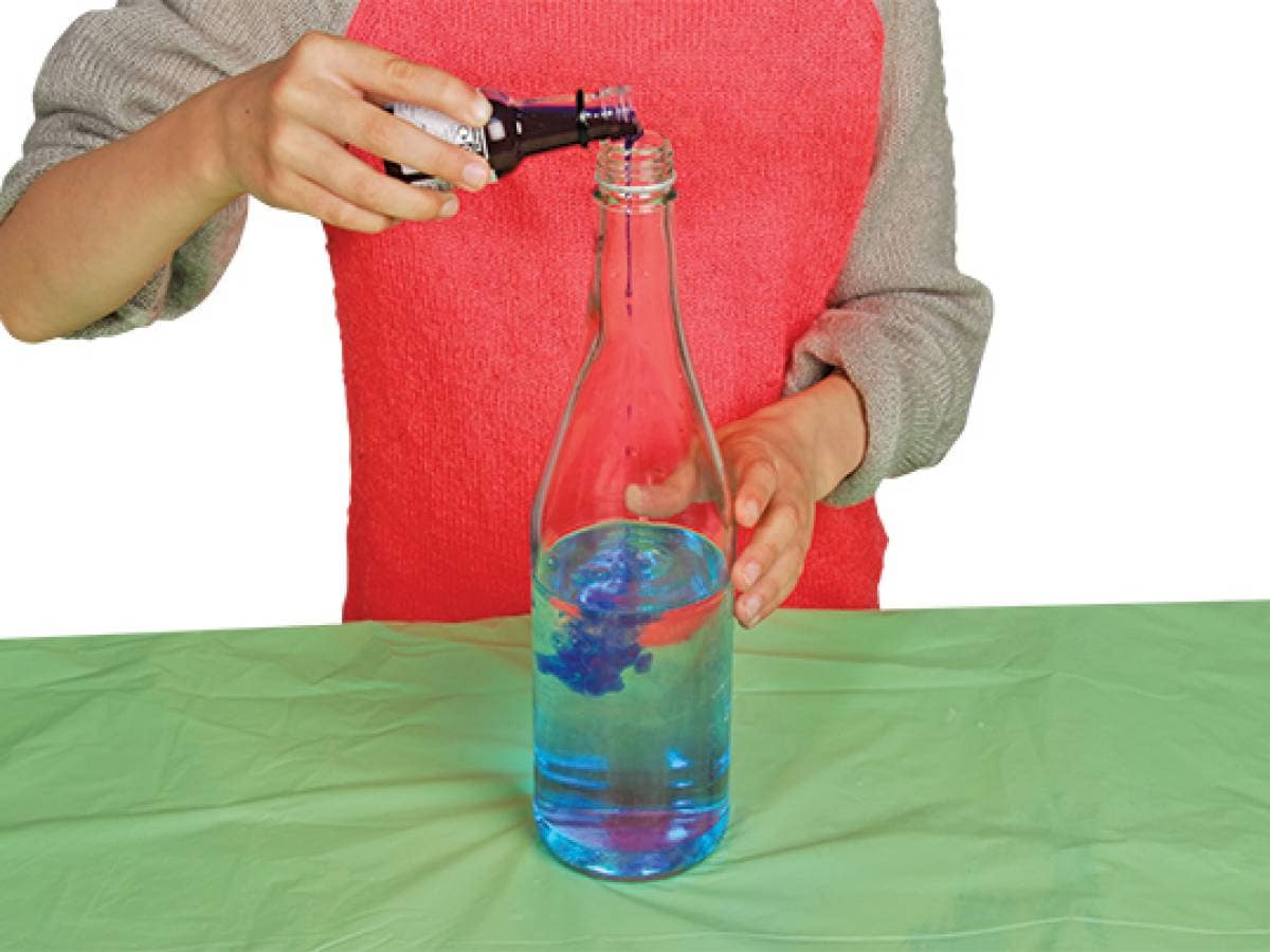 Person pouring blue food colouring into the bottle
