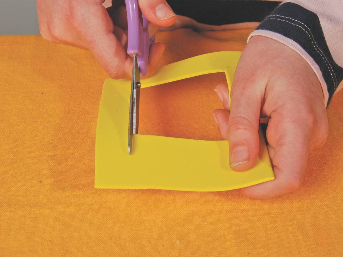Person cutting out a yellow square