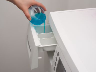 Liquid being poured into the dispensing drawer of a washing machine.