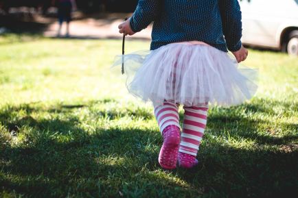 a young girl in a tutu walks across grass