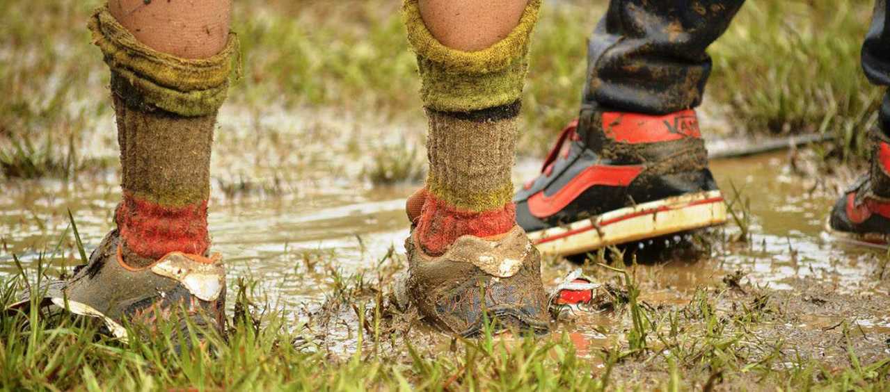 Two boys' legs covered in mud and grass stains.