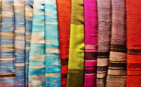 Close up of colourful fabrics lined up together.