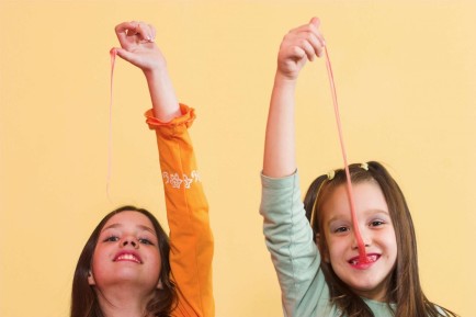 Two happy girls playing with chewing gum.