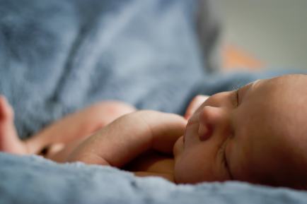 A young baby sleeping on a blue blanket.