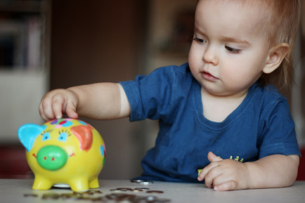 young child playing with toy money box