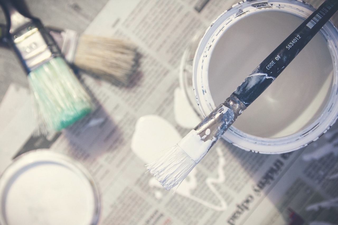 A pot of white household paint with a dripping brush.