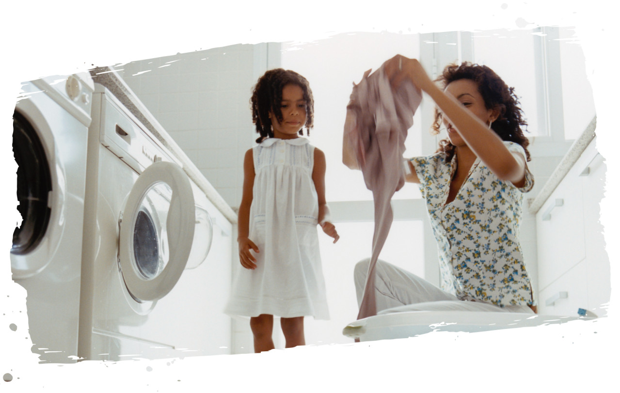 Mother and daughter putting laundry in a washing machine