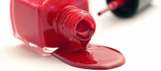 Red nail varnish spilling out of an upended bottle.