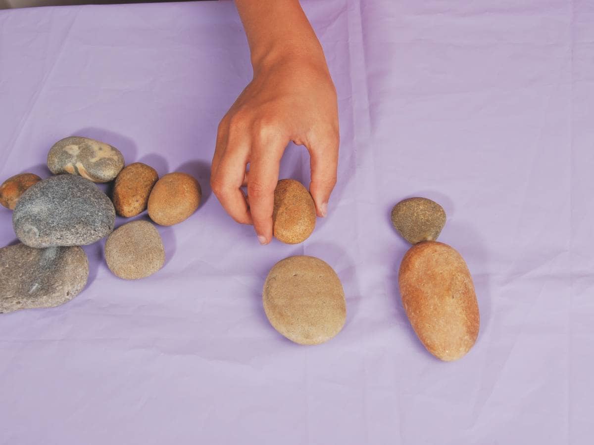 Pebbles on a purple table cloth with a hand selecting one